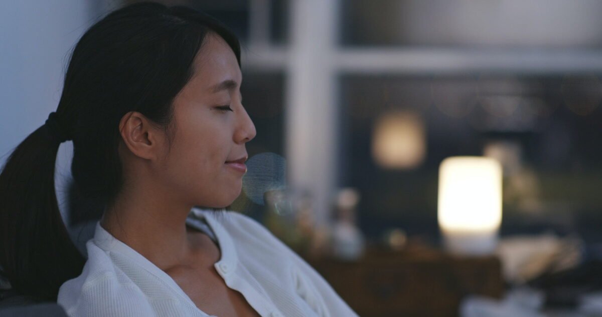 Woman taking a deep breath at home in the evening